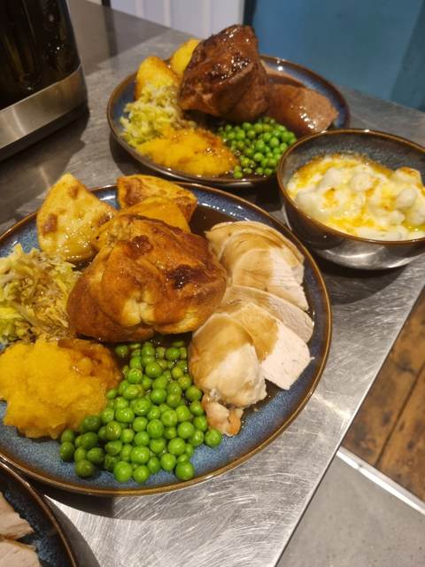 A Sunday roast with sliced meat, a Yorkshire pudding, roast potatoes, peas, swede and cabbage, with cauliflower cheese alongside
