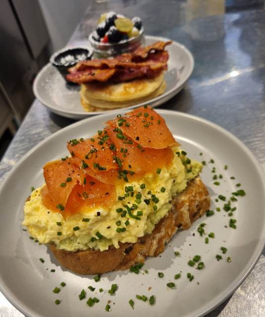 Scrambled egg and avocado on seeded toast, topped with smoked salmon and chives